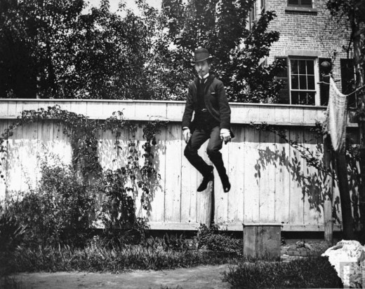 A-man-in-a-suit-and-bowler-hat-jumping-in-the-air-in-a-backyard-in-Brooklyn-New-York-1890-520x413